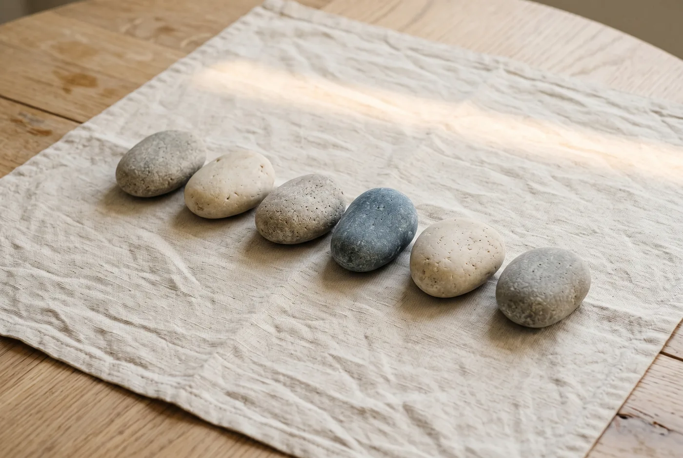 Seis piedras en fila sobre una tela de lino, a la luz de la mañana